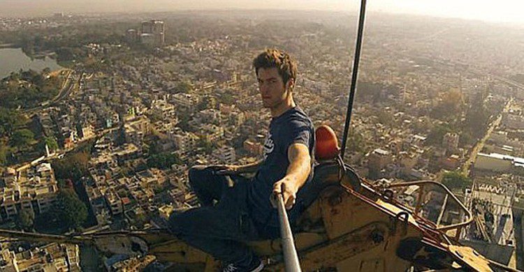 Jeune homme en train de prendre une photo du haut d'une grue