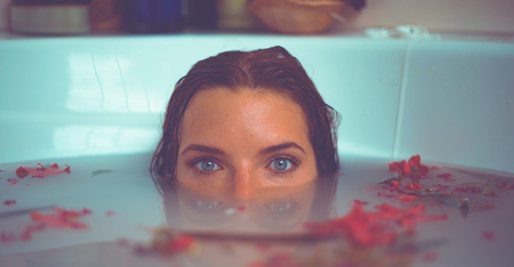 Femme le visage à moitié immergé dans l'eau de son bain.